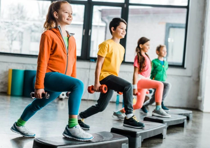 Four students exercising on step platforms, each holding weights.